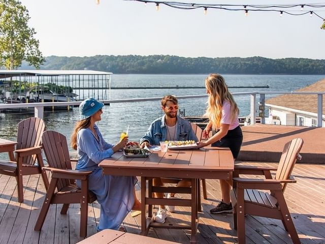 Guests being served tacos on a sunny waterfront deck at Eddy’s Lakeside Bar in Shangri-La Resort and Golf Club