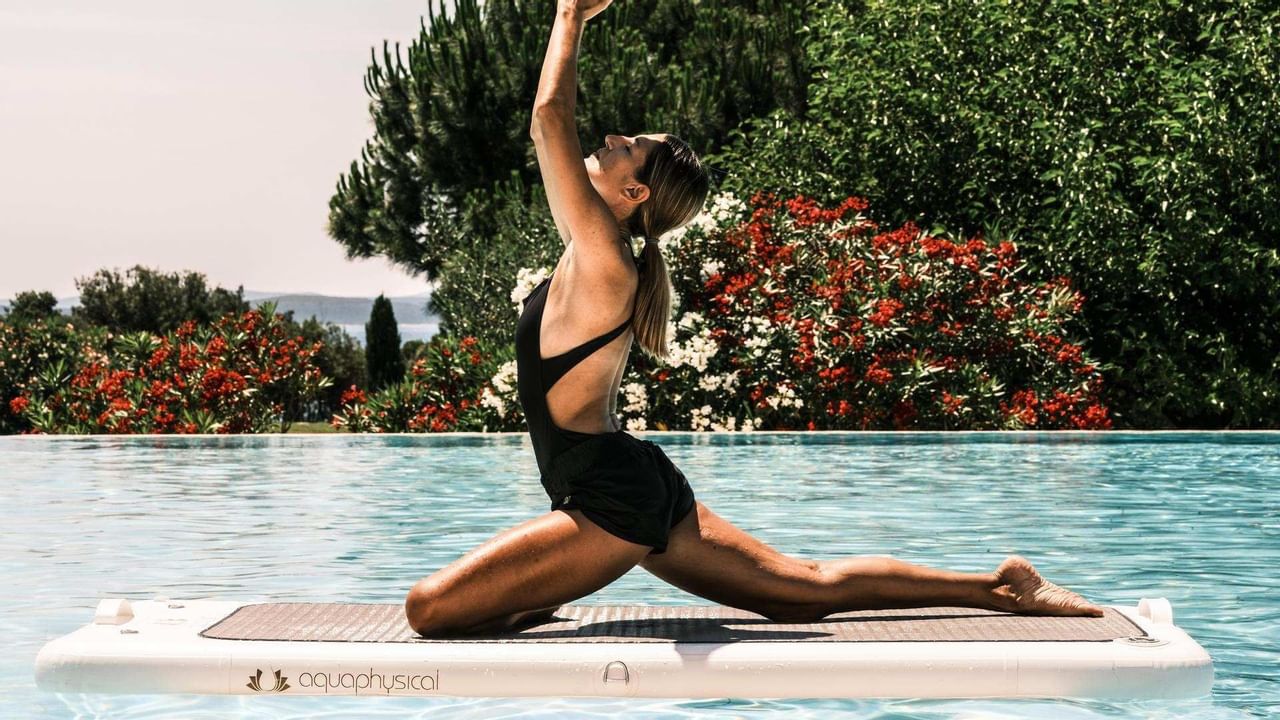 Lady doing yoga by the pool at Falkensteiner Hotel & Spa Iadera