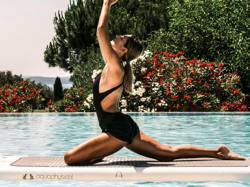 Lady doing yoga by the pool at Falkensteiner Hotel & Spa Iadera