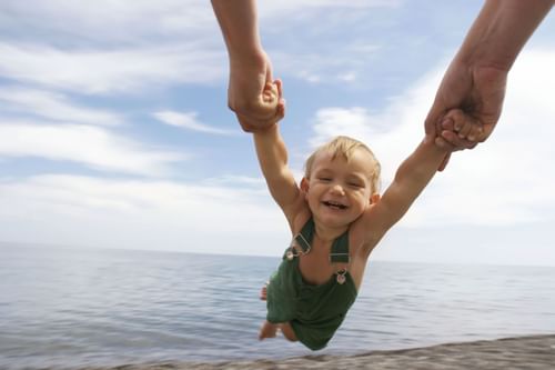 Child playfully being lifted off ground on beach