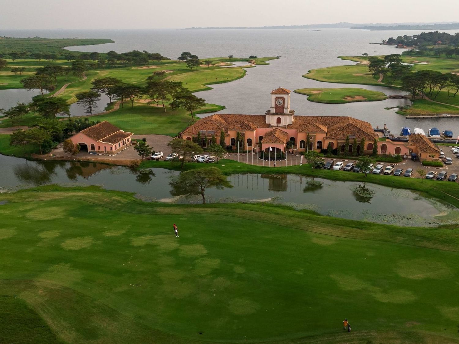 Aerial view of golf course surrounding terracotta-roofed clubhouse beside lake near Lake Victoria Serena Golf Resort & Spa