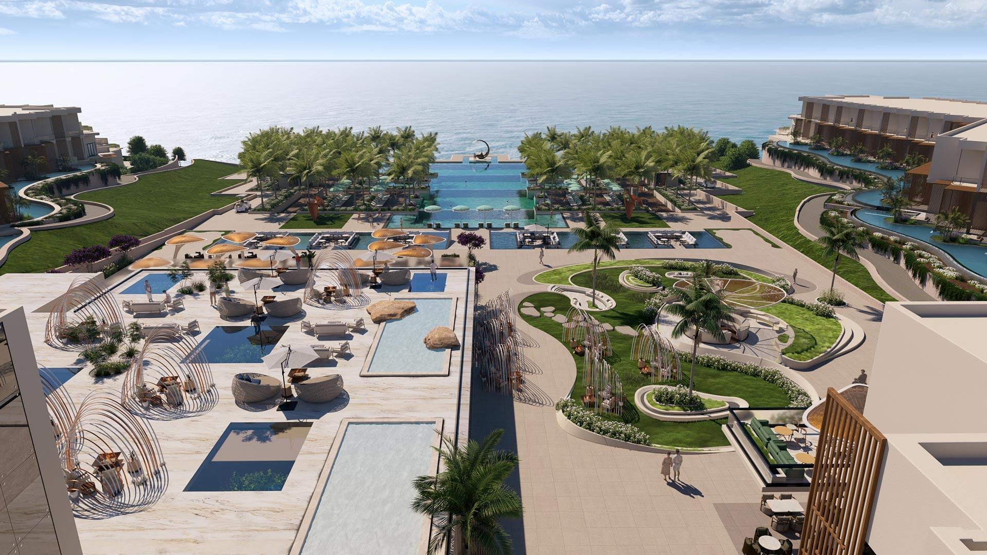 An aerial view of the resort with pools, palm trees, and ocean backdrop.