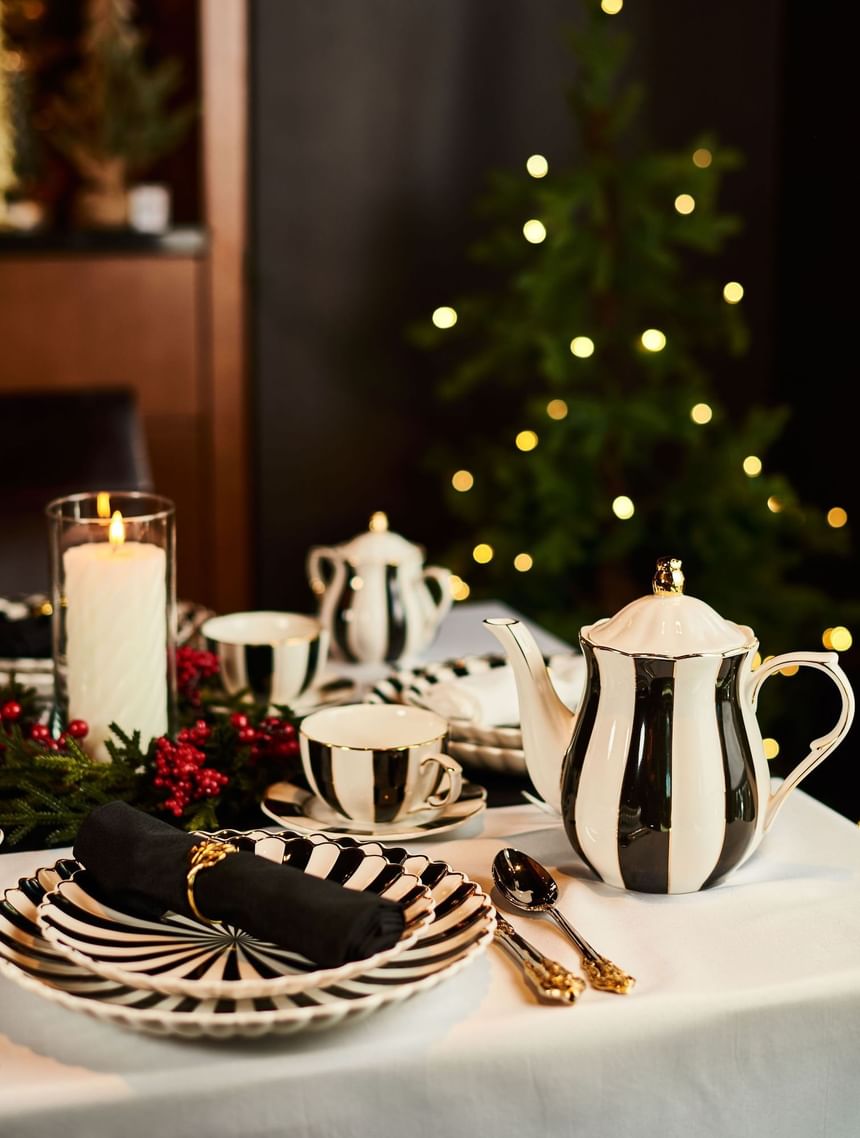Festive table setting with black and white striped dishes, candles, and a Christmas tree at Hotel Arista
