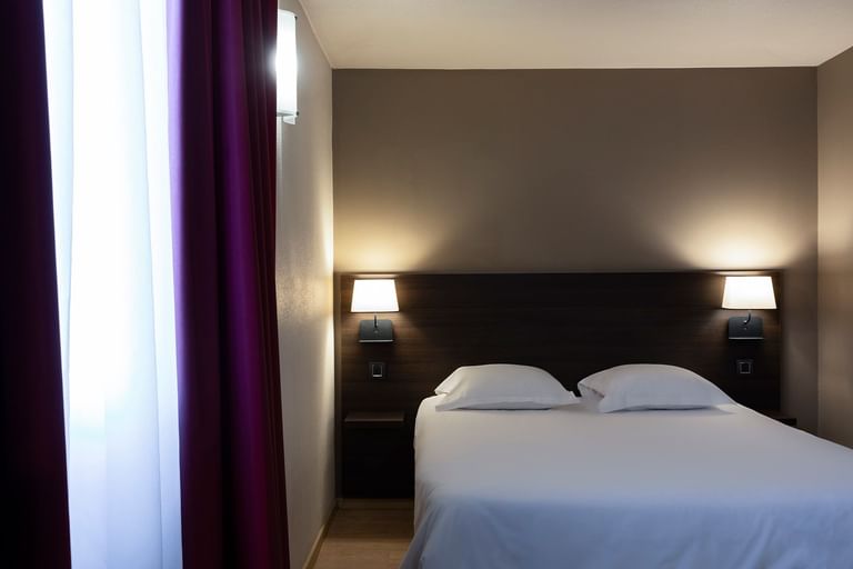 Queen bed in a room at Escale Oceania Aix-en-Provence