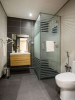 Standard room bathroom featuring a vanity by the glass shower at Naviti By Warwick Dammam