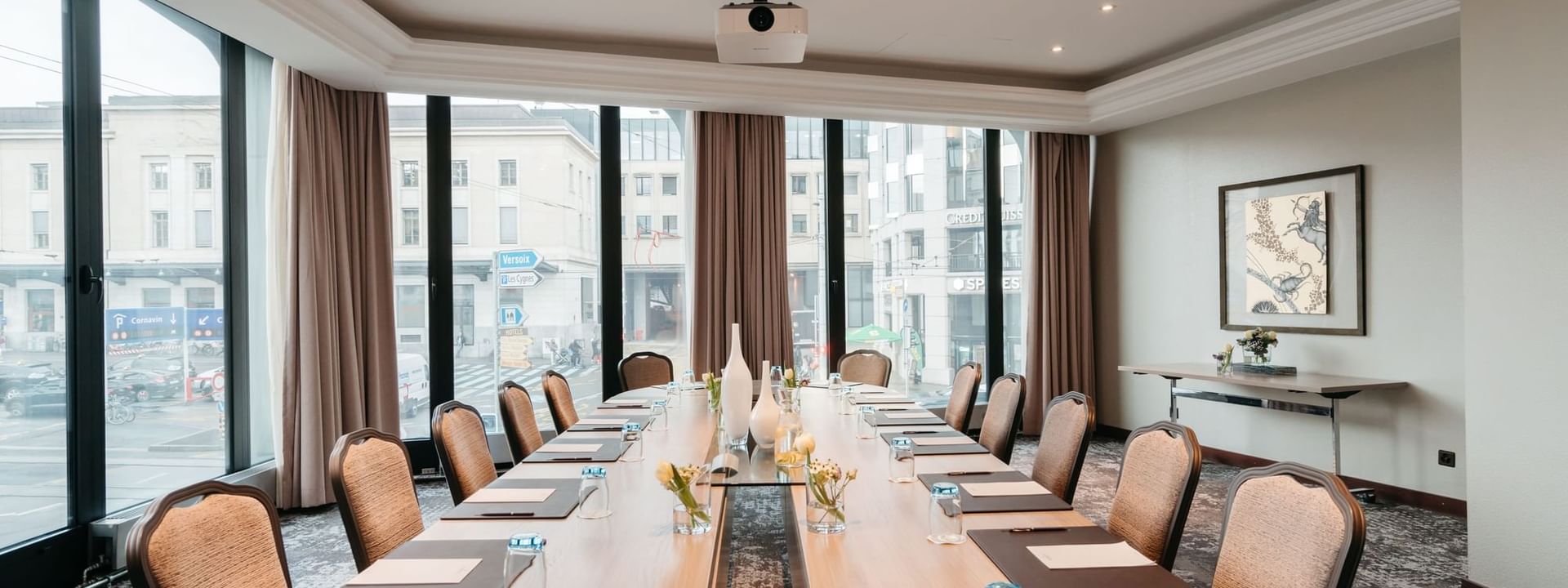 Long wooden table by tan chairs under a projector in Rigi at Warwick Geneva
