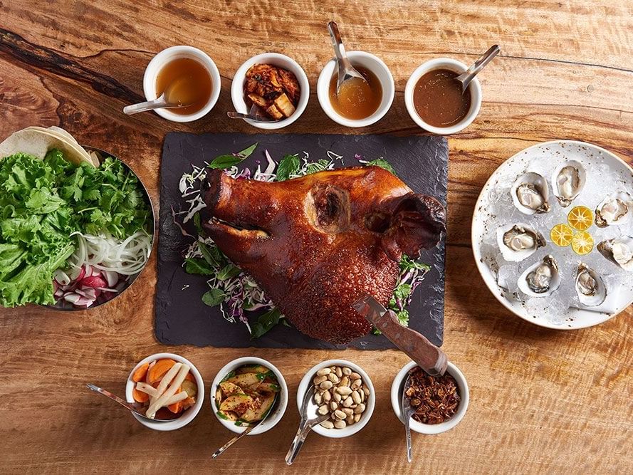 Roasted pig head served with spices & gravy on a table in The Pig and The Lady near Waikiki Resort Hotel by Sono