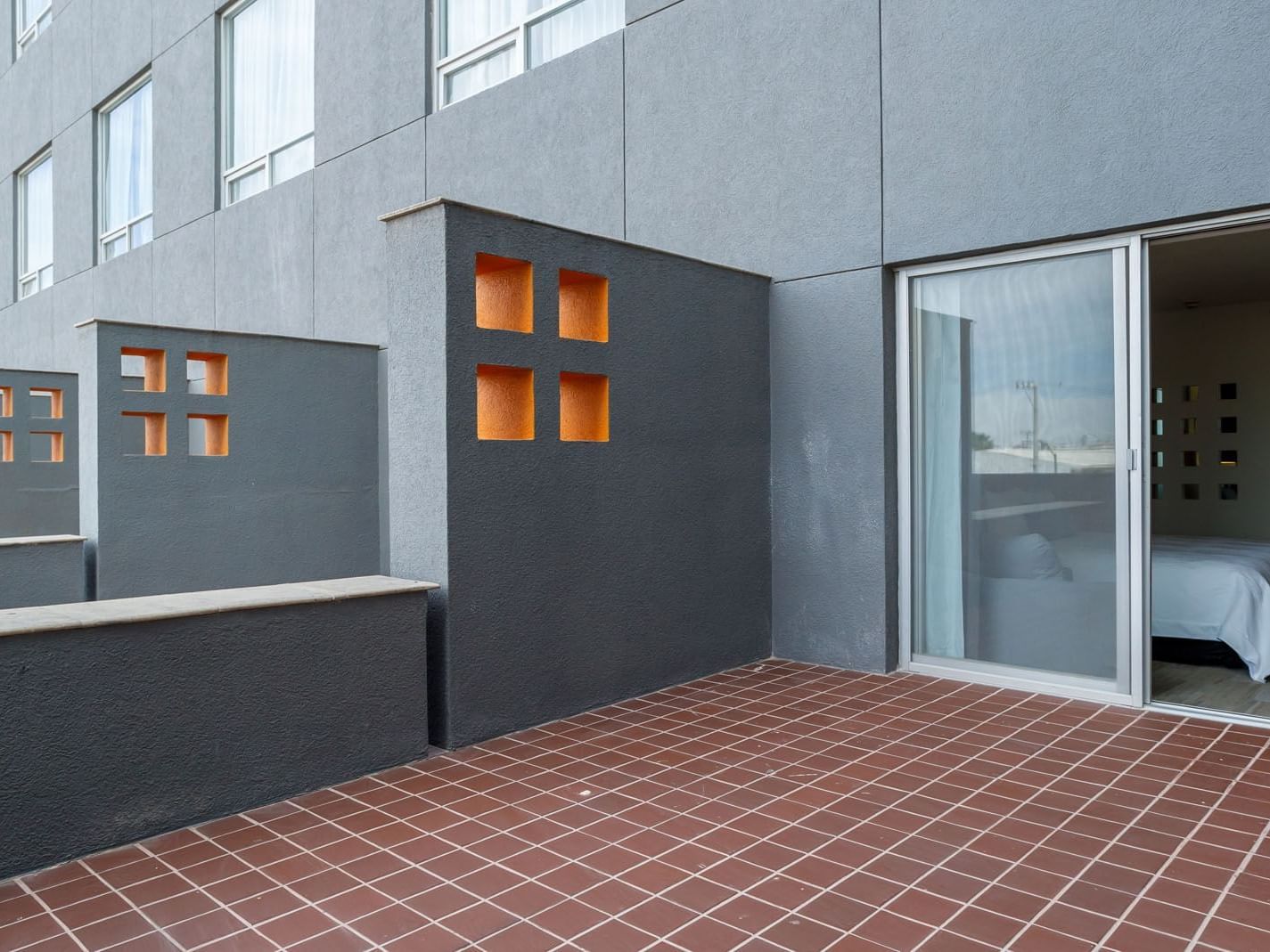 King Deluxe Superior room private terrace featuring red floor tiles and modern grey architectural walls at Real Inn Torreon