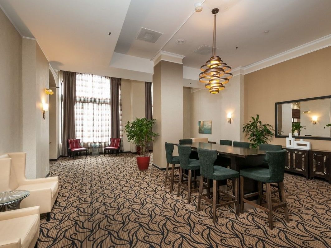 Elegant dining area with table, chairs, and plants in a hotel lobby.