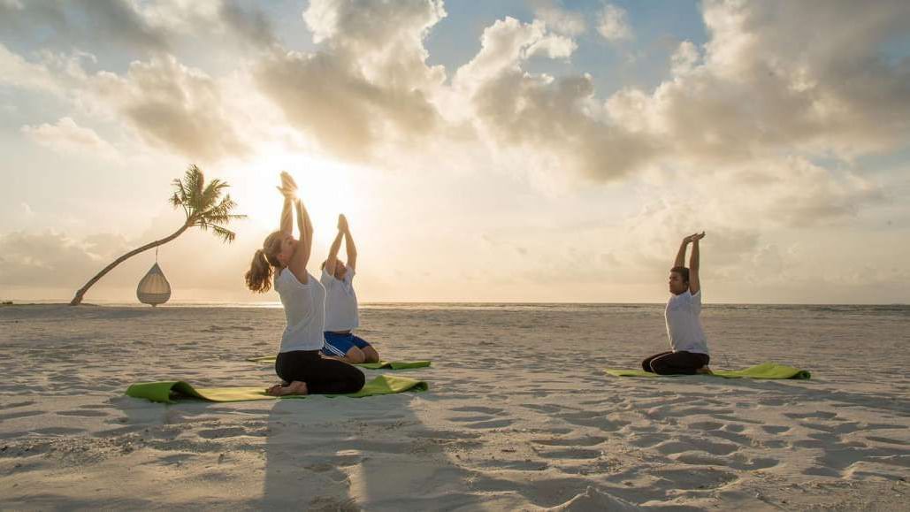 3 people engaged in yoga on the beach, The Signature Collection