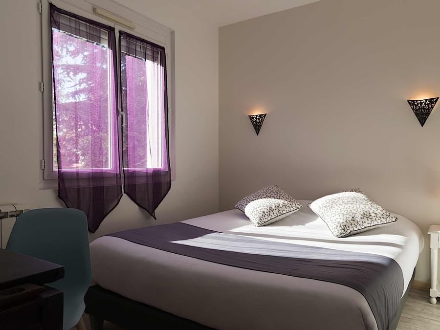 Warm bed by a window in Suite with Jacuzzi at Originals Hotels