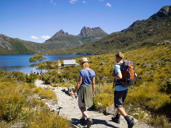 Couple walking on a trail by river near Cradle Mountain Hotel 