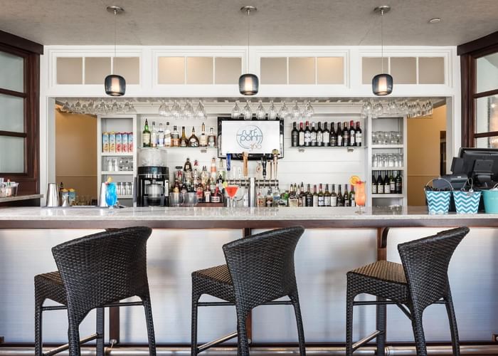 A modern looking bar area with three wicker bar stools at Ogunquit Collection