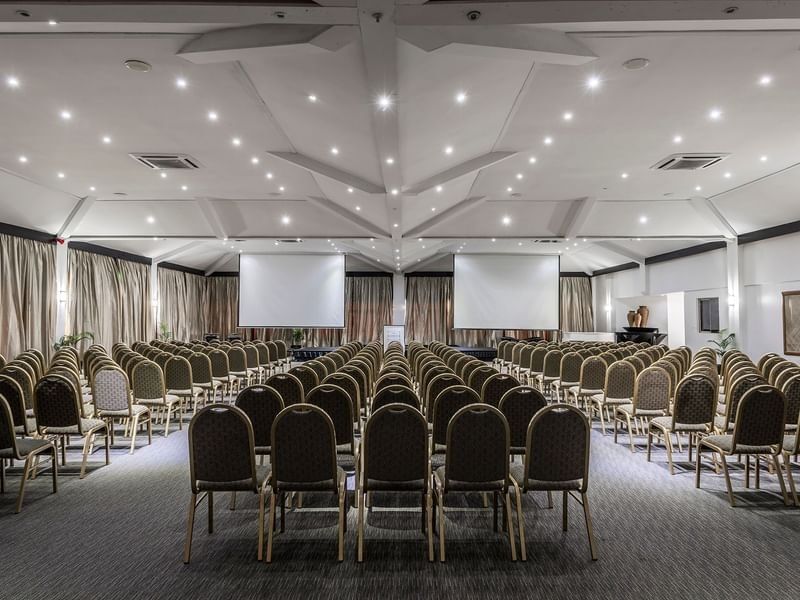 Vusu Boardroom with rows of chairs by two large screens under a white vaulted ceiling at Warwick Fiji Resort and Spa