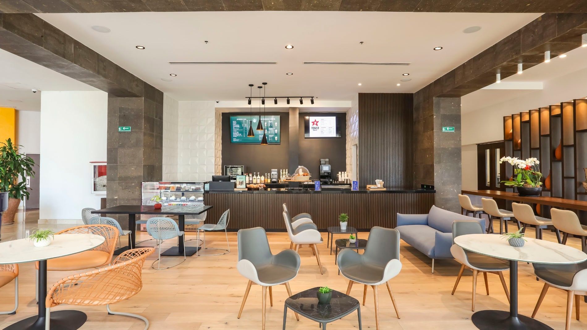 Bright modern Token Cafe with marble tables, colorful chairs, and a sleek snack counter at Camino Real Veracruz