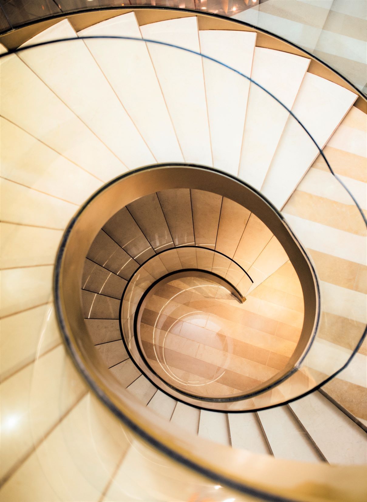 Overhead view of a spiral staircase with beige & brown steps at Almanac Group