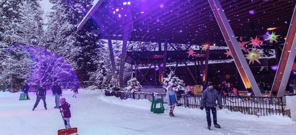 Winter event at Whistler Olympic Plaza with snow falling lights and families gathered outdoors