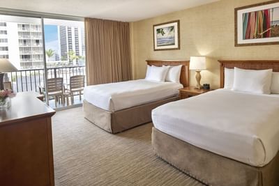 Two double beds arranged with a private balcony view in Standard at Waikiki Resort Hotel by Sono