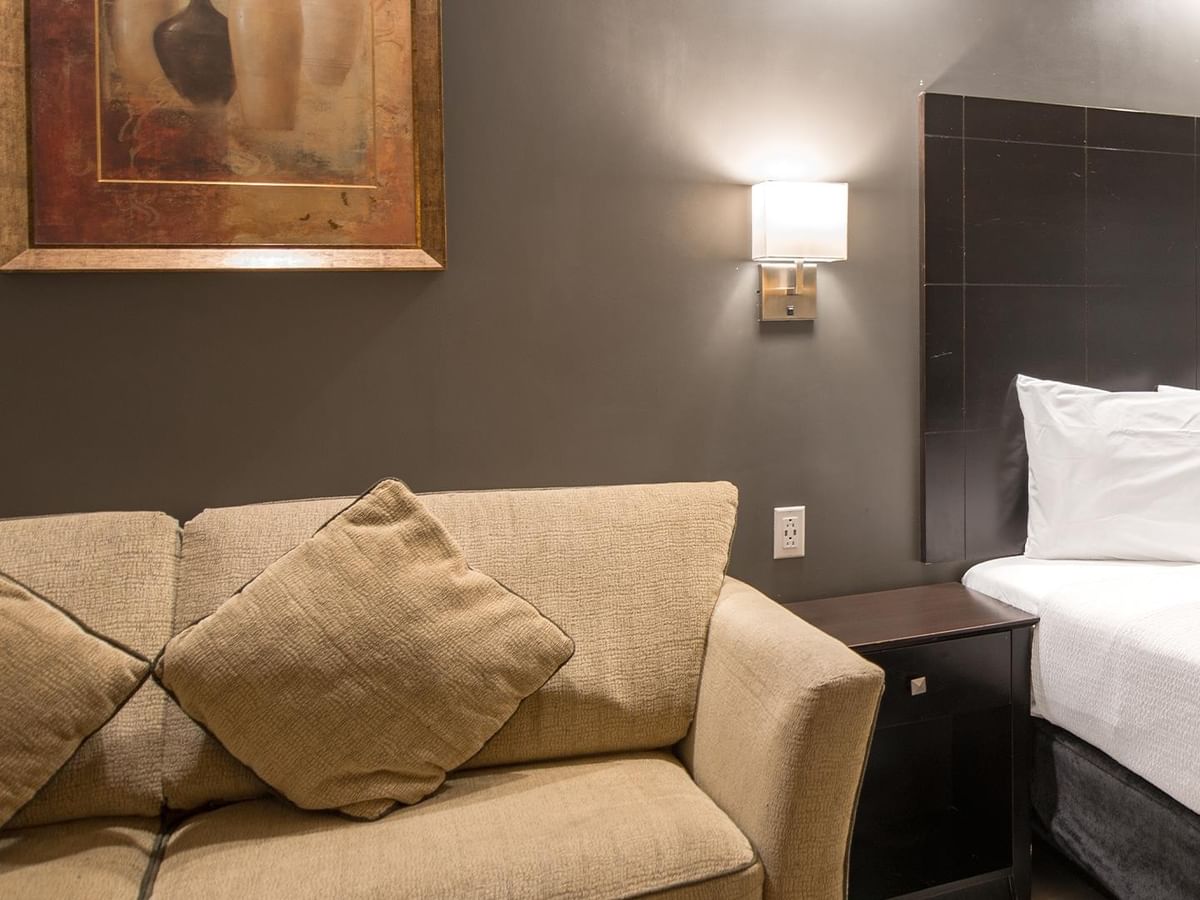 Accessible room with couch, framed artwork, and queen bed.