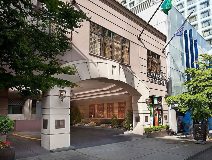 The main entrance of The Paramount Hotel Seattle on a sunny day with trees and a valet parking sign