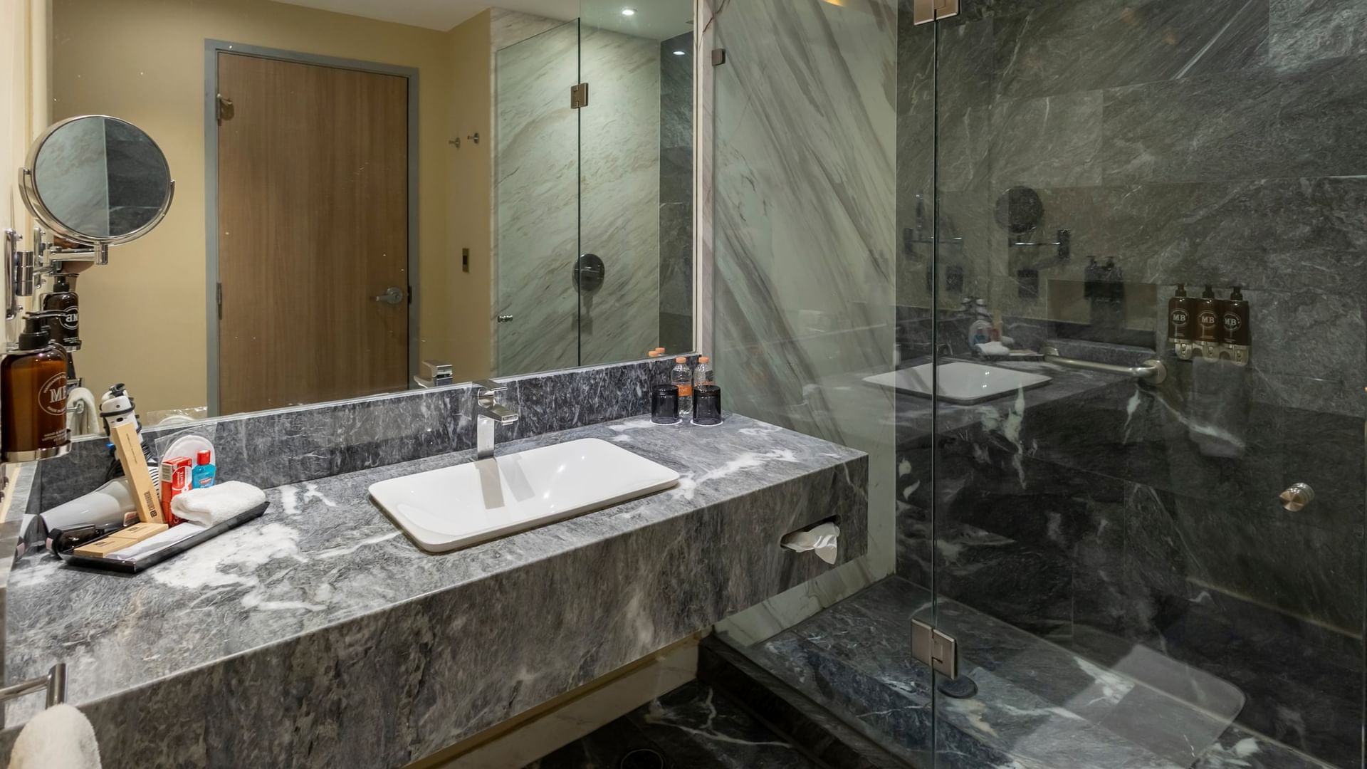 Baño moderno con mármol gris, lavabo rectangular, ducha de vidrio y amenidades en Camino Real Fashion Drive Monterrey