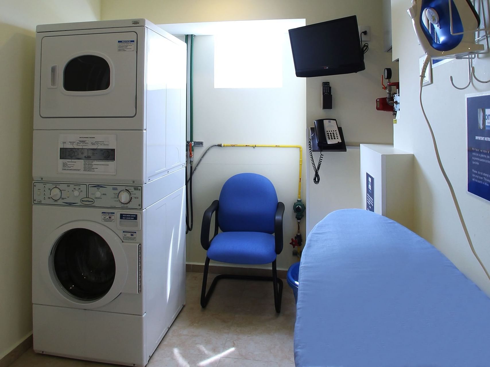 Lavadora, secadora y silla en la sala de lavandería de One Hotels