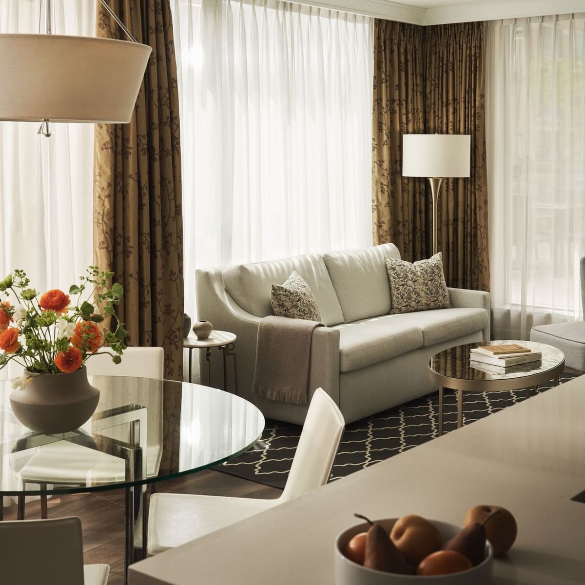 A cozy living room with a couch, coffee table, dining set, and kitchen with pears in a bowl.