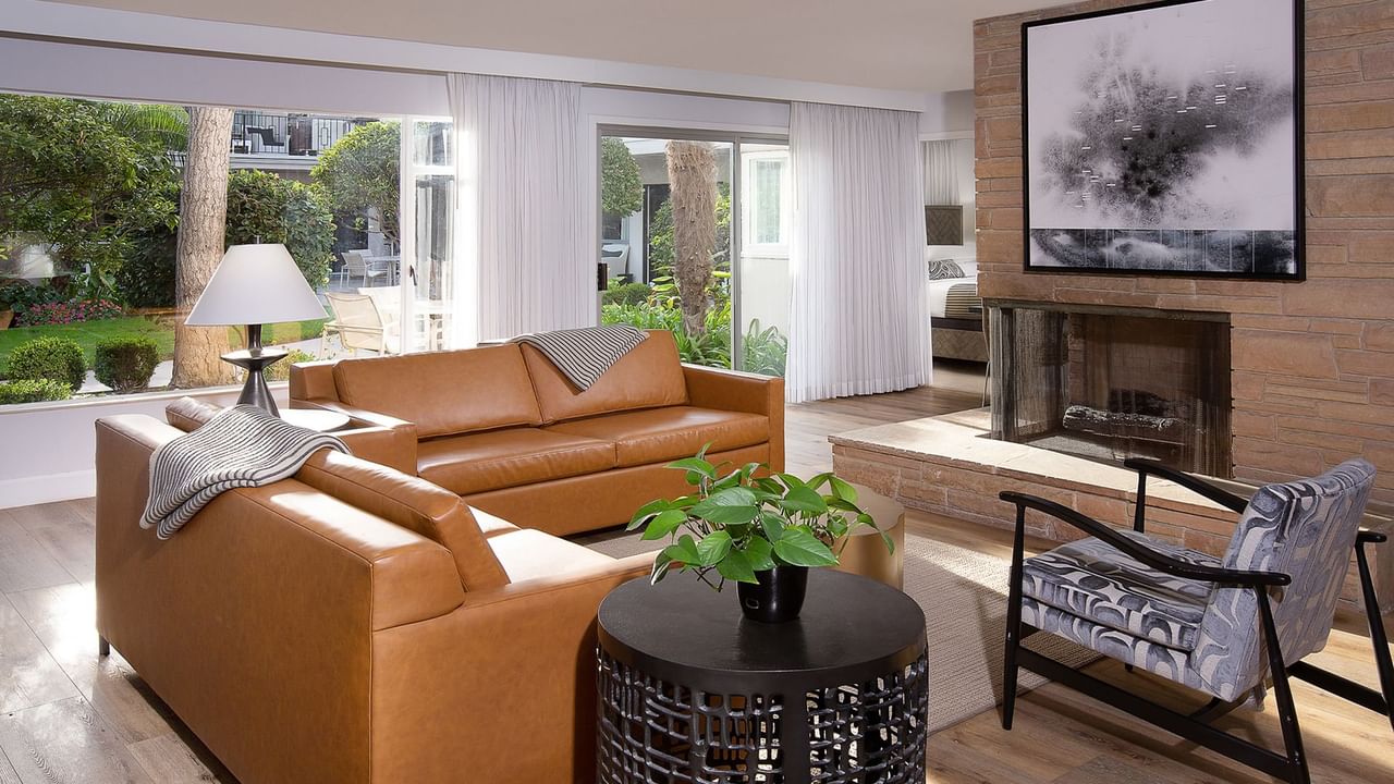 A living room with two brown couches, a round table, a fireplace, and a large window.