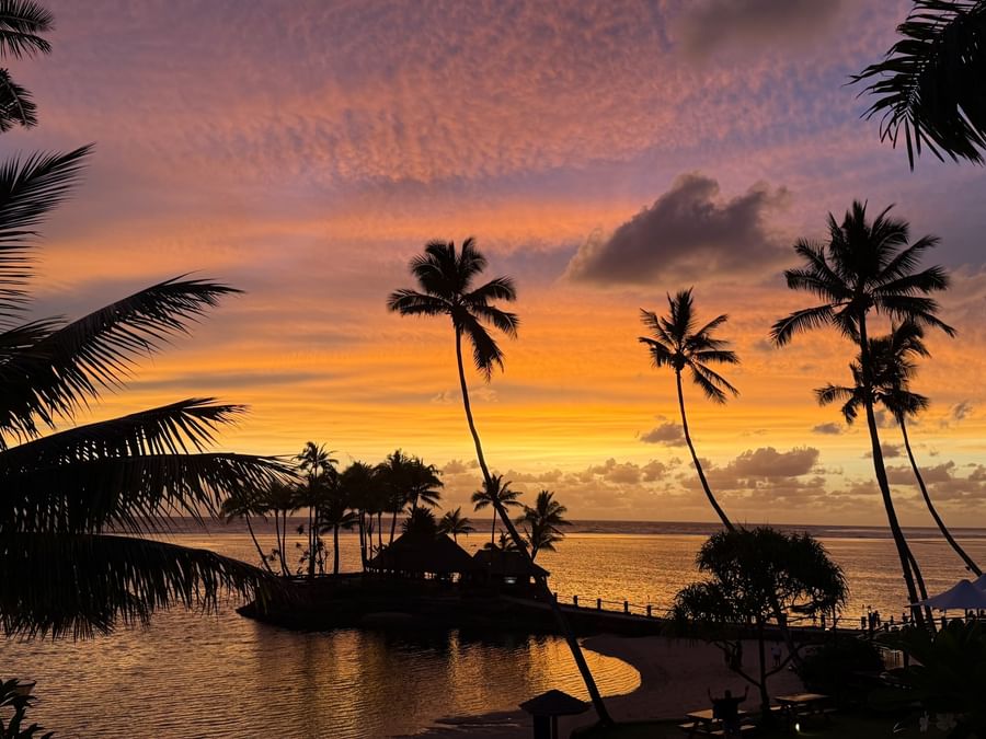 Sunset view over a tropical beach with palm trees at Warwick Fiji Resort and Spa.