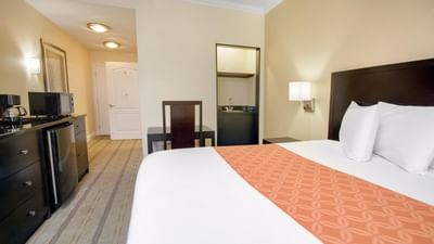 Bed by a desk & kitchenette in the ADA King Room at Galleria Palms Hotel, an affordable hotel near Disney World for families