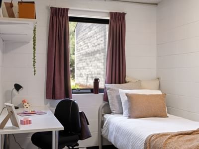 Bedroom with single bed, desk, and window at UniLodge at Curtin University.