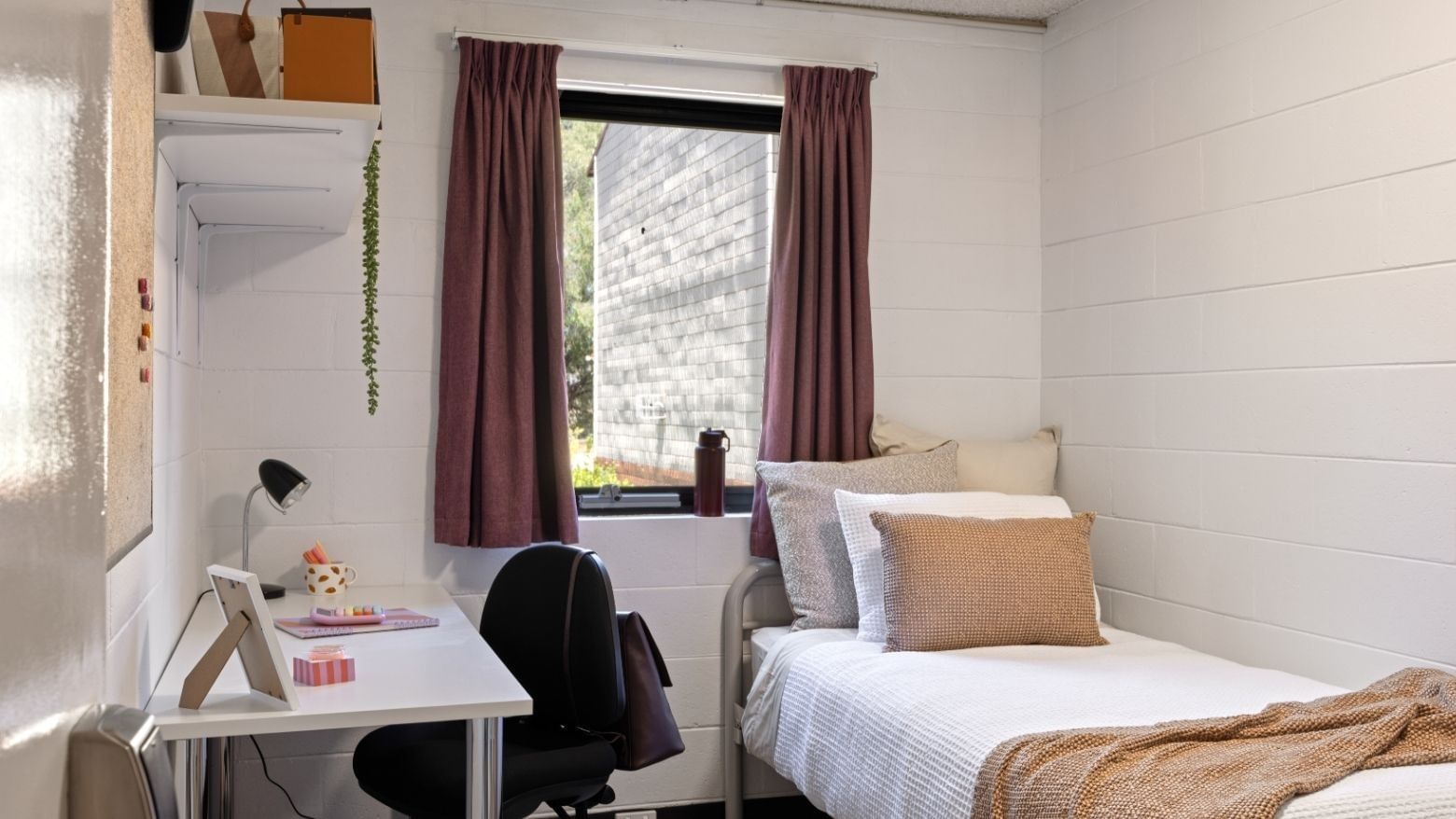 Bedroom with single bed, desk, and window at UniLodge at Curtin University.