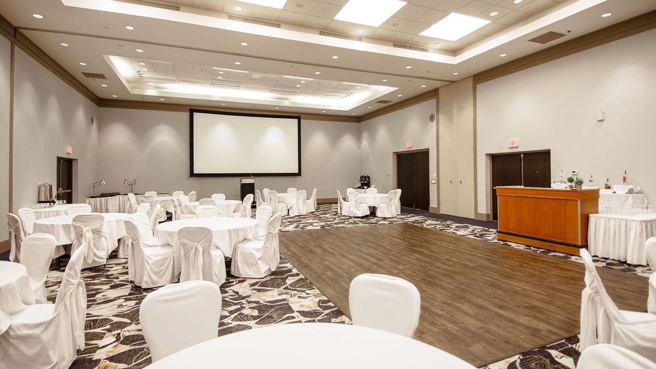 A large event room with round tables and chairs.