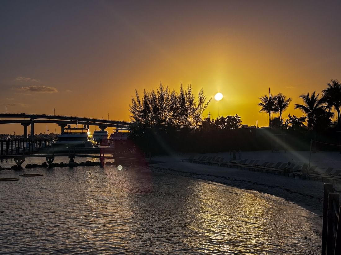 Golden sun by a bridge under a glowing sky surrounding rows of beach loungers near Warwick Paradise Island Bahamas