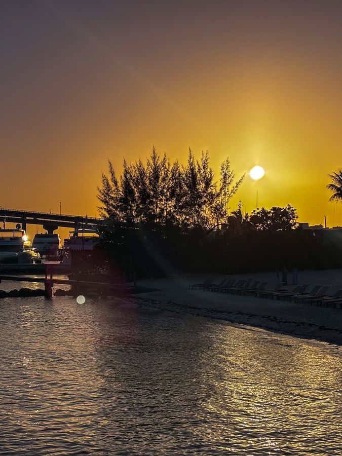 Golden sun by a bridge under a glowing sky surrounding rows of beach loungers near Warwick Paradise Island Bahamas