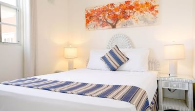 Bed with blue striped pillow between matching nightstands and lamps in Junior One Bedroom at Worthing Court Apartment