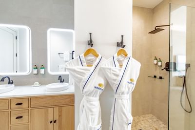 Two plush bathrobes hanging on hooks in Two Bedroom Beachfront Pool Junior Suite bathroom at Windsong Resort On The Reef