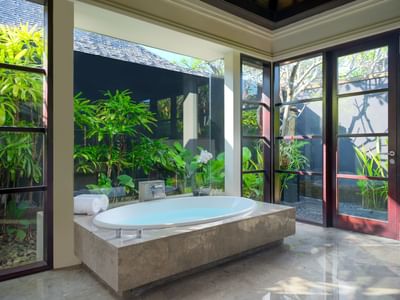 Modern bathroom with large bathtub and garden view at Peppers Seminyak