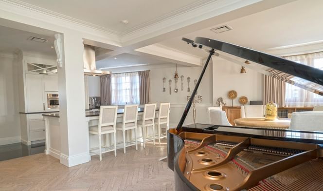 Lounge area with piano, bookshelves, and dining table in Royal Suite at Hotel Port Royal