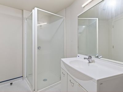 White bathroom with shower, sink, and mirror at UniLodge Stafford House.