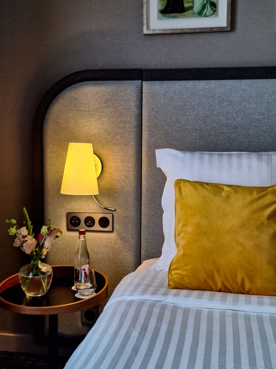 Close-up of a nightstand by the cozy bed with a cushioned headboard in the Executive Suite at Warwick Reine Astrid - Lyon