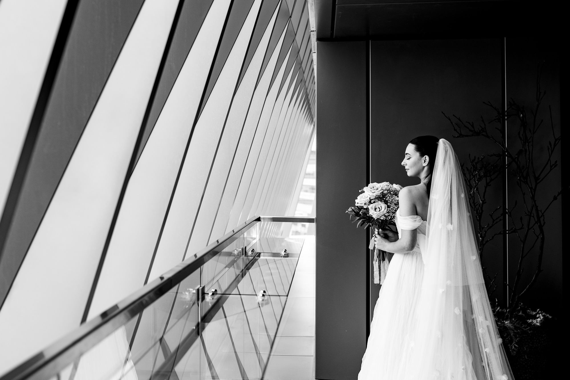 Monochrome image of a bride overlooking the outside from the balcony at The Londoner Hotel
