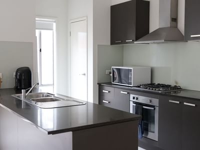 Modern kitchen with sink, oven, microwave, and toaster at La Trobe University Regional Housing.