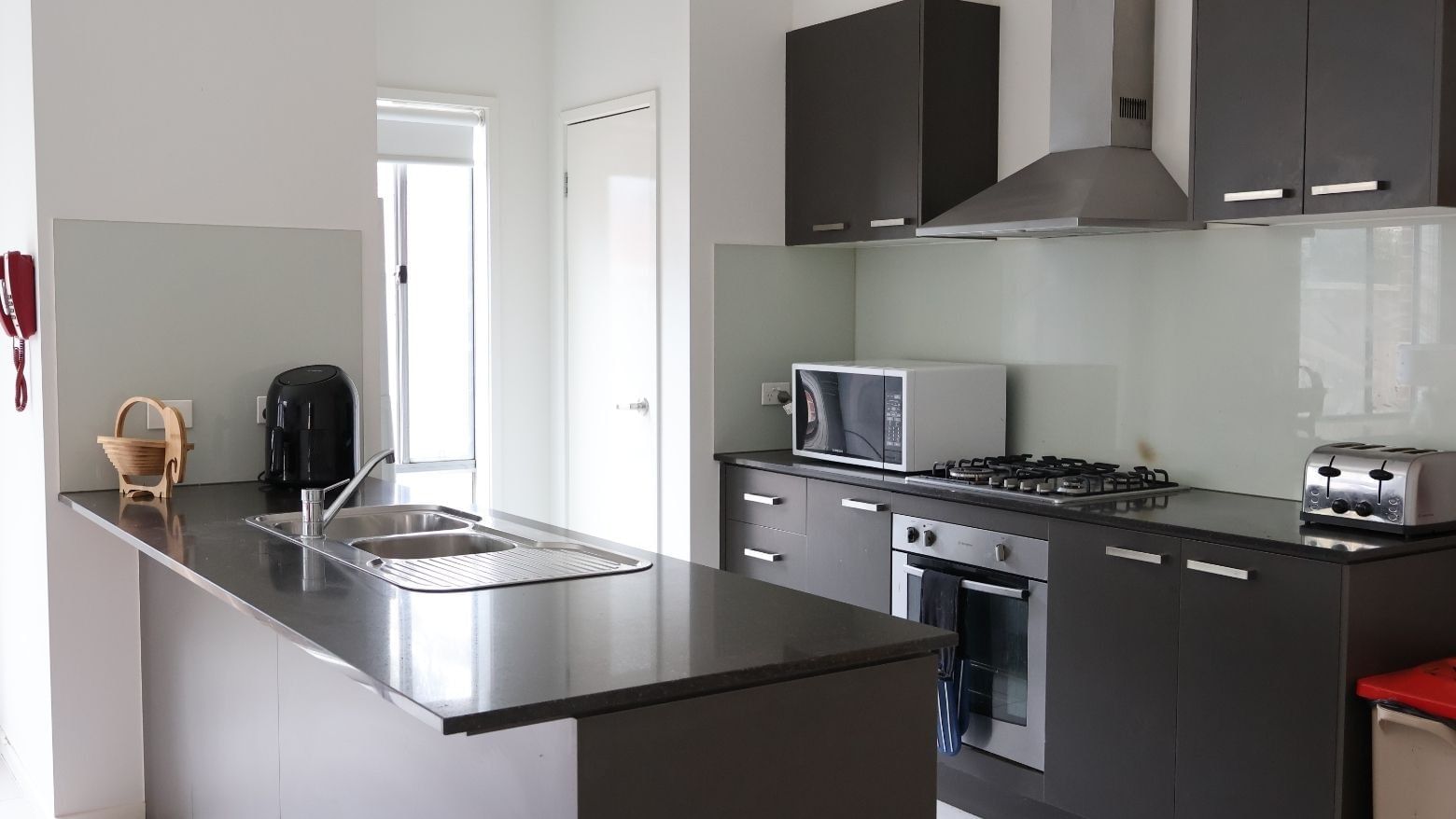 Modern kitchen with sink, oven, microwave, and toaster at La Trobe University Regional Housing.