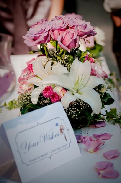 Elegant floral arrangement at The Saujana Hotel Kuala Lumpur with pink roses, white lilies, and a wedding details card
