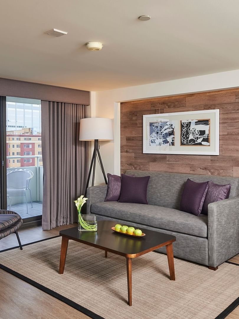 Gray sofa with purple pillows by a coffee table in Denver Suite near a balcony view at Warwick Denver