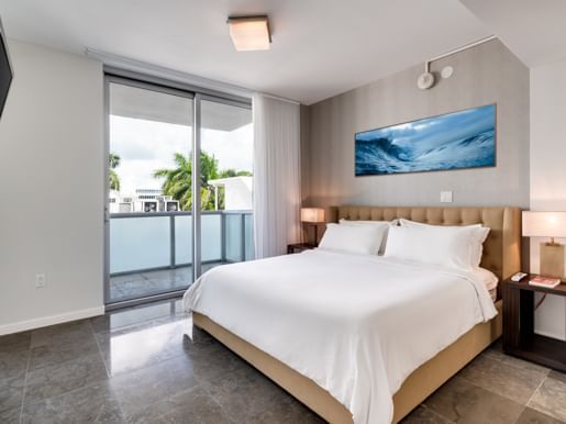 Bedroom with large bed, sliding glass doors, ocean view, TV, and modern decor.