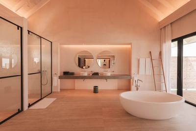 Modern Water Pool Villas bathroom at Ananea Madivaru Maldives with a bathtub, double sinks, glass shower, and soft lighting