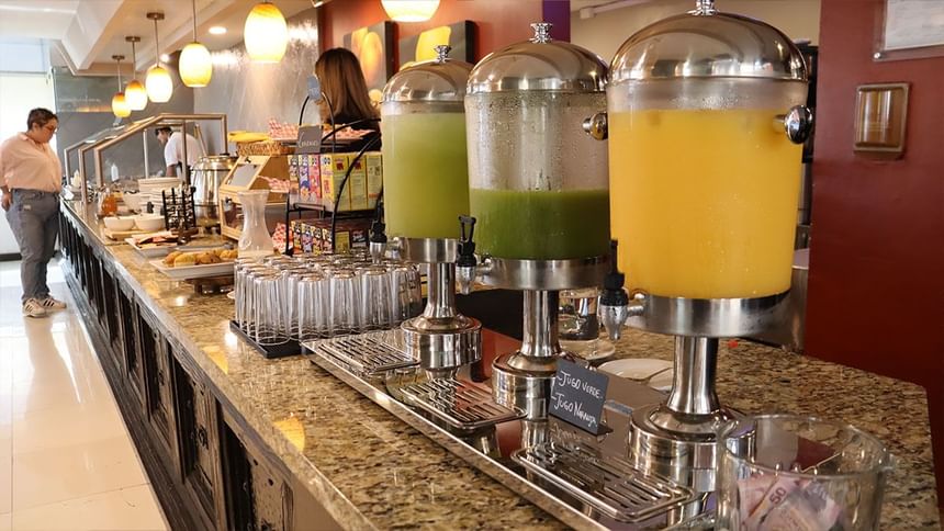 Tres dispensadores de jugo en un mostrador de granito del bufé de desayuno en Fonda De Hermosillo, Araiza Hotels 