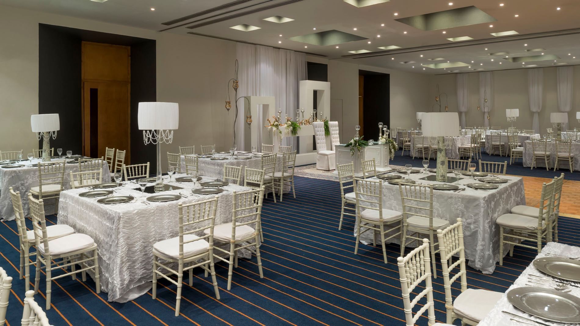 Ciudad de México event setup showcasing elegant white chairs and tall, ornate table lamps at Real Inn Nuevo Laredo